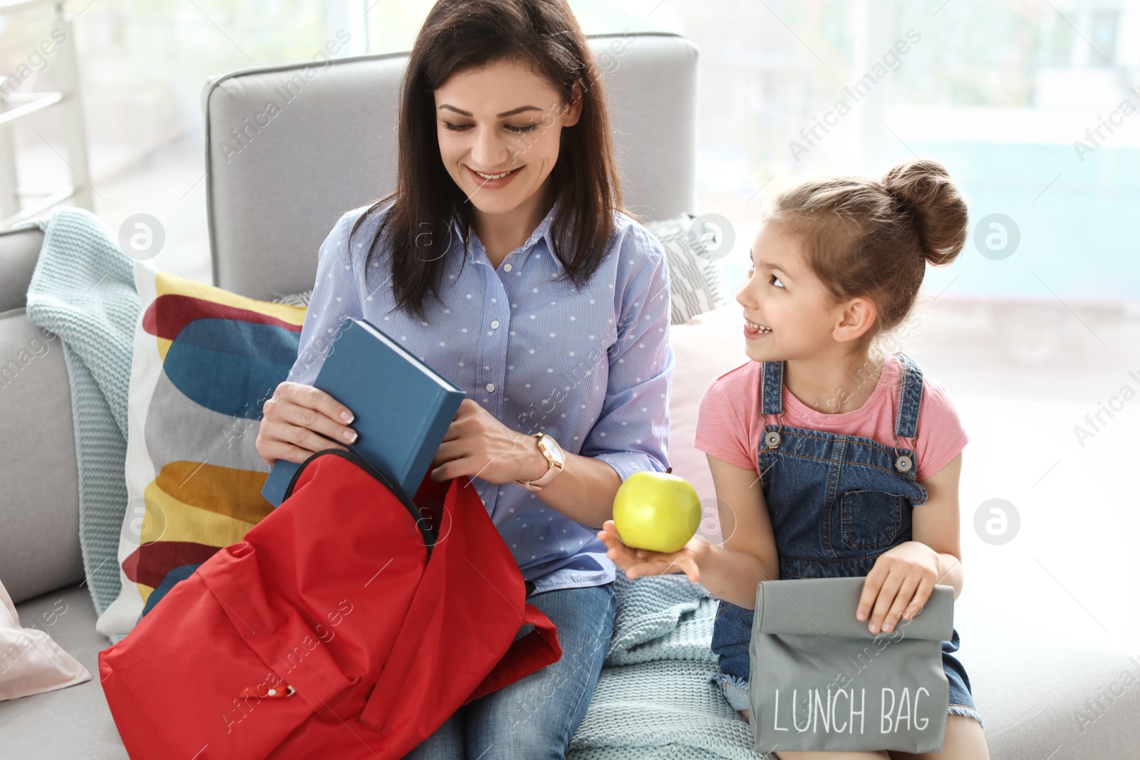 Photo of Young woman helping her little child get ready for school at home