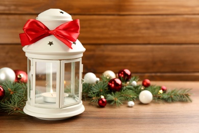 Photo of Christmas lantern with burning candle and festive decor on wooden table. Space for text