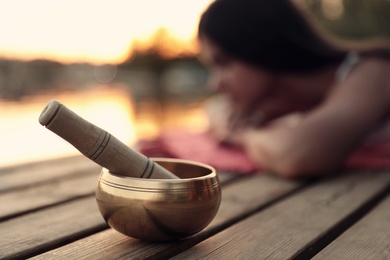 Woman at healing session outdoors, focus on singing bowl