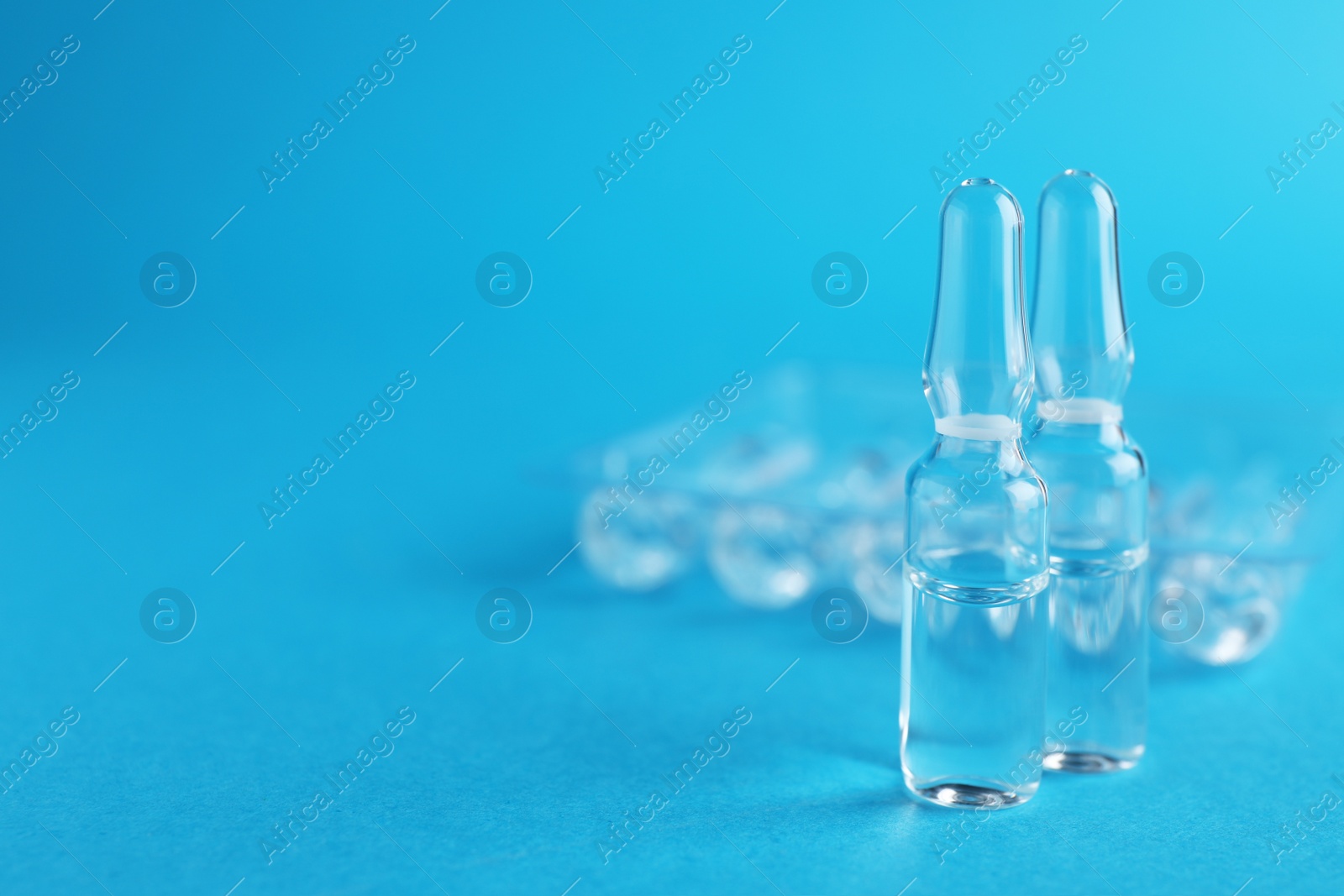 Photo of Many medical ampoules with solution on light blue background. Space for text