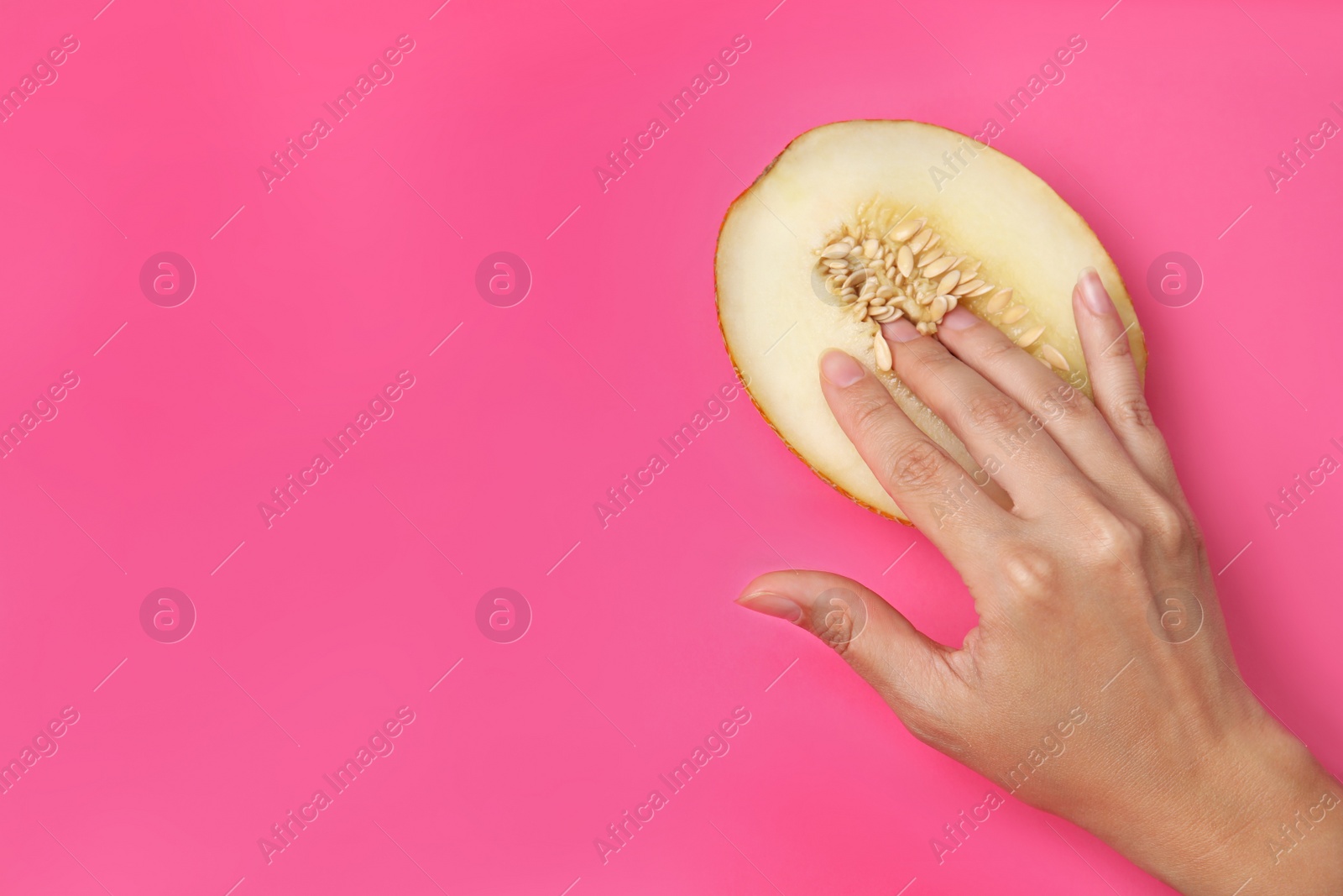 Photo of Young woman touching half of melon on pink background, top view with space for text. Sex concept