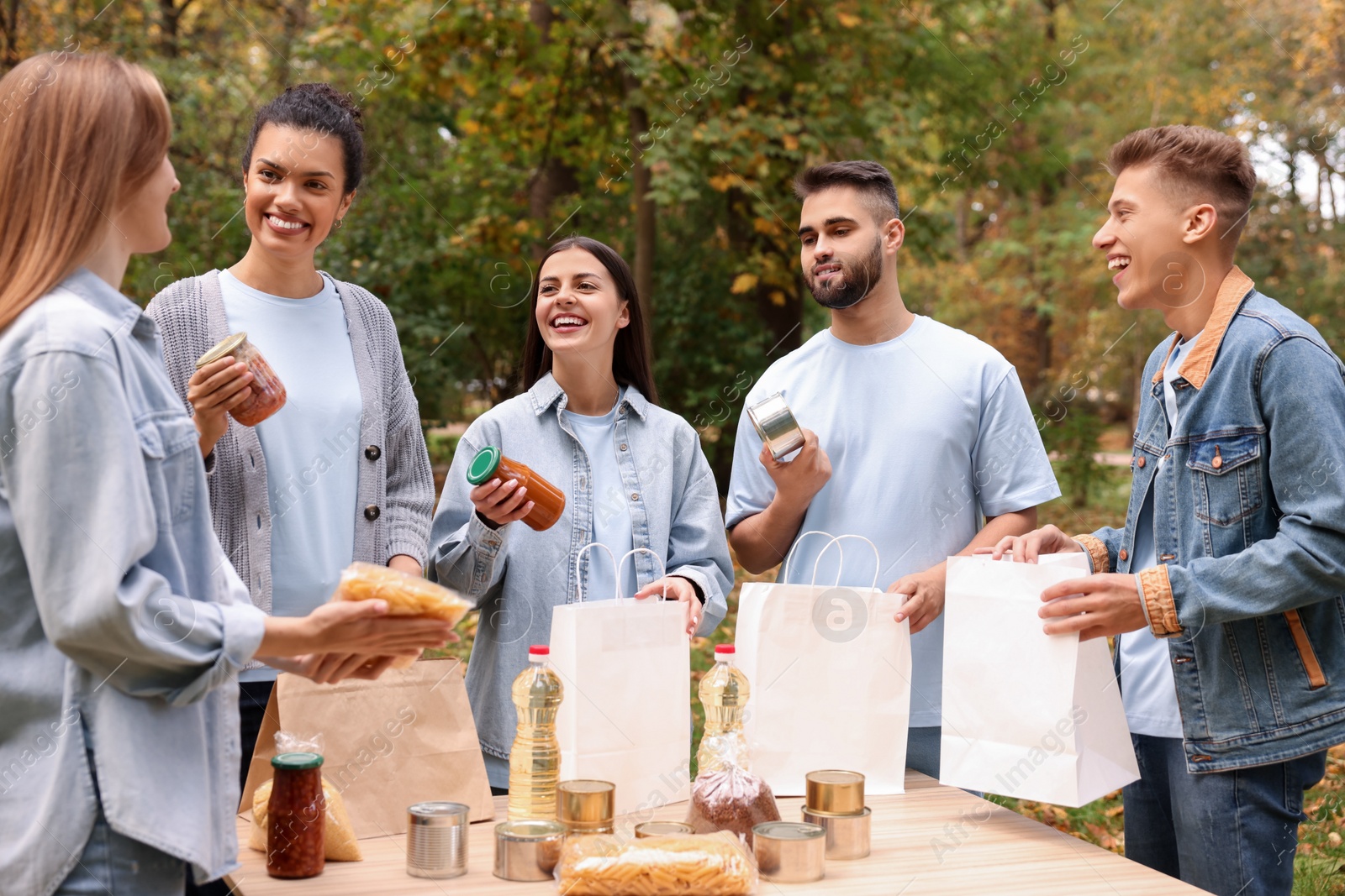 Photo of Group of volunteers packing food products at table in park