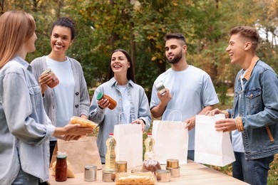 Photo of Group of volunteers packing food products at table in park