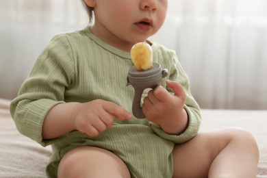 Photo of Cute baby girl with nibbler on bed at home