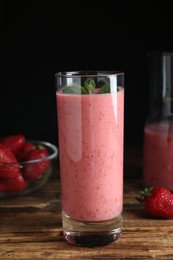 Photo of Tasty strawberry smoothie with mint in glass on wooden table