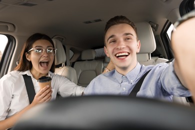Photo of Happy young couple taking selfie in car