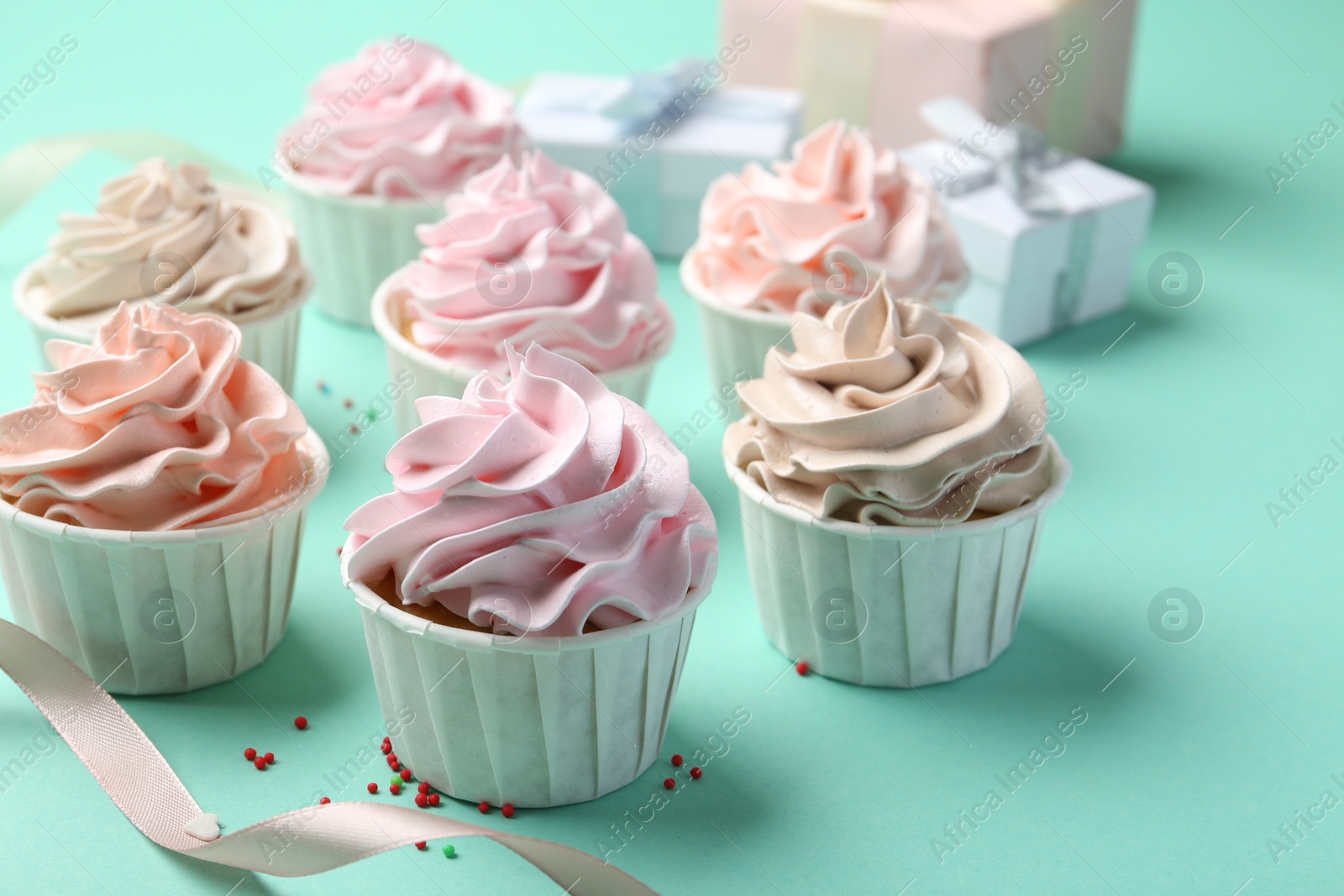 Photo of Delicious birthday cupcakes, ribbon and sprinkles on turquoise background, closeup