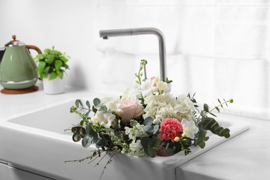 Photo of Bouquet of beautiful flowers in kitchen sink