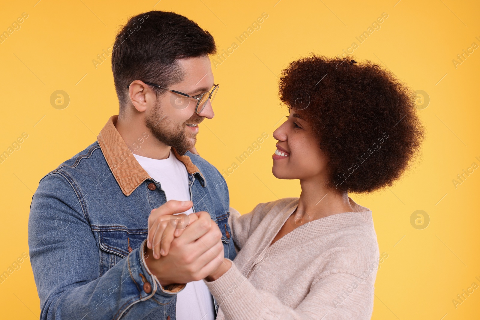 Photo of International dating. Lovely couple dancing on orange background