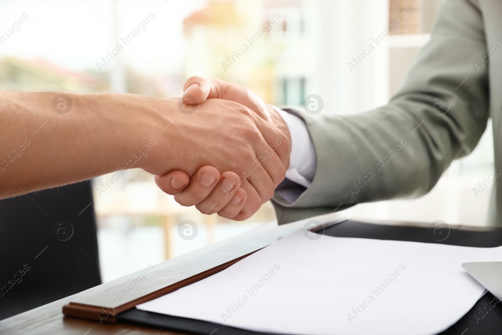 Photo of Business partners shaking hands at table after meeting in office, closeup