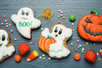 Photo of Tasty cookies and sweets for Halloween party on blue wooden table, flat lay
