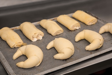 Photo of Different unbaked pastries on tray in workshop