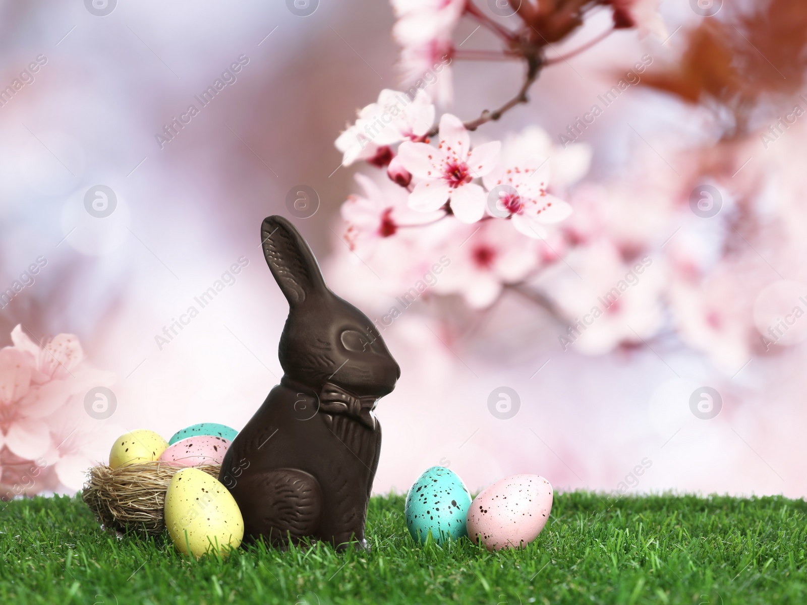 Image of Chocolate bunny and eggs on green grass outdoors. Easter celebration