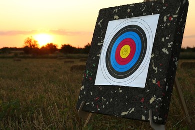Photo of Tripod with archery target in field at sunset
