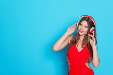 Sexy young woman in bikini listening to music on color background