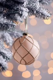 Christmas tree decorated with holiday ball against blurred lights, closeup