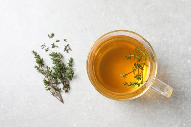 Photo of Aromatic herbal tea with thyme on light grey table, flat lay