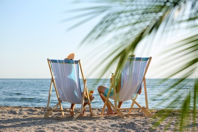 Photo of Young couple with cocktails in beach chairs at seacoast