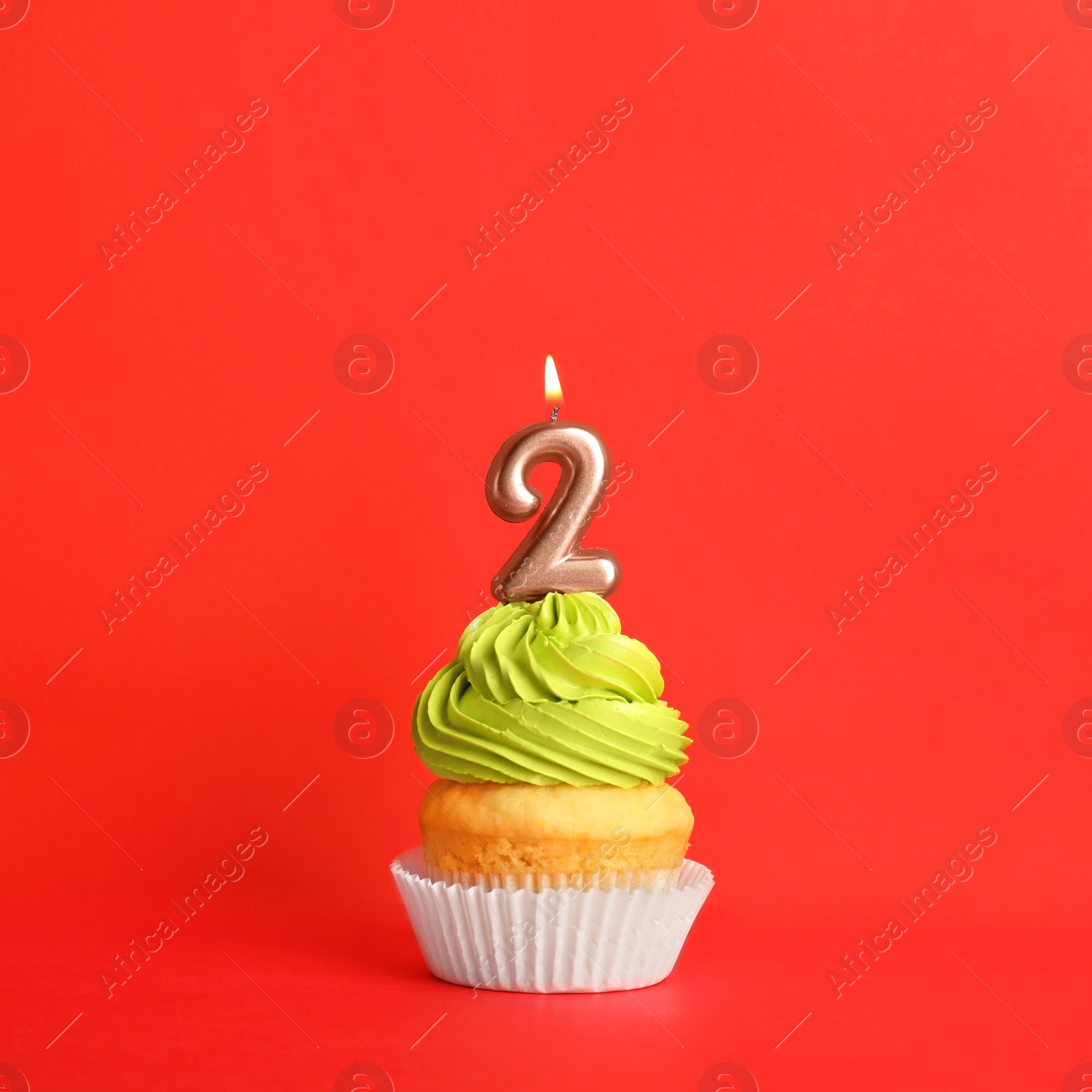 Photo of Birthday cupcake with number two candle on red background