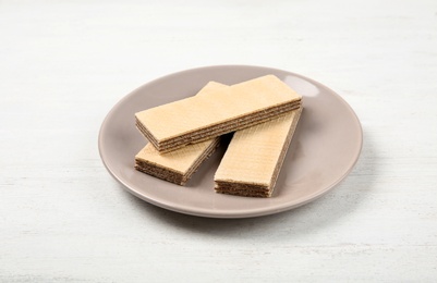 Plate with delicious crispy wafers on white wooden table