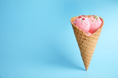 Photo of Delicious ice cream in wafer cone on blue background. Space for text