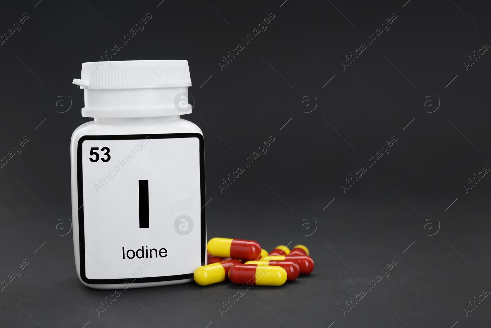 Photo of Plastic jar and iodine pills on black background. Space for text
