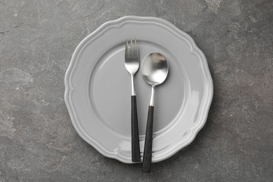 Photo of Stylish setting with cutlery and plate on grey textured table, top view