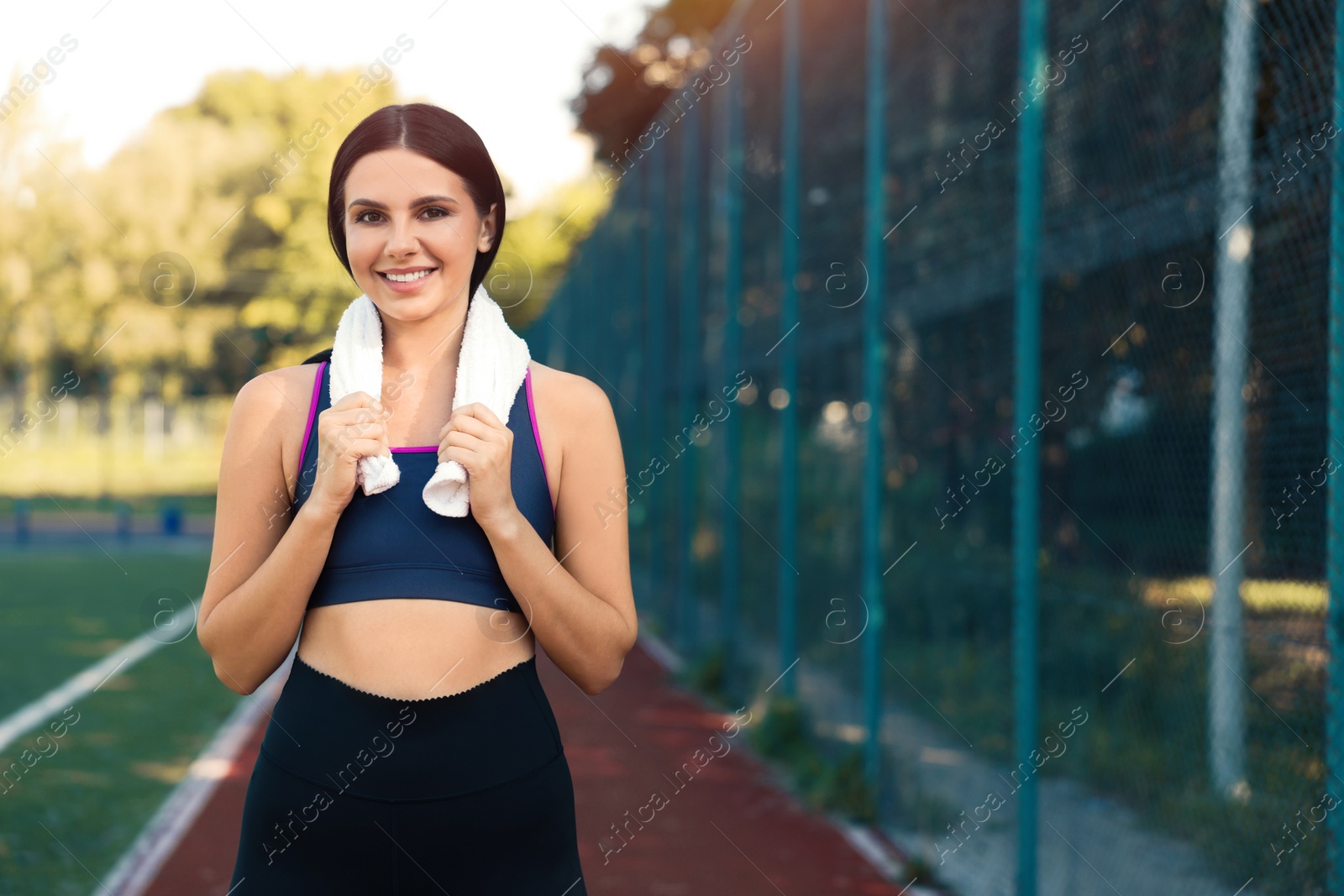 Photo of Smiling woman in sportswear with towel at game court. Space for text