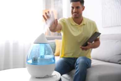 Photo of Man near modern air humidifier at home