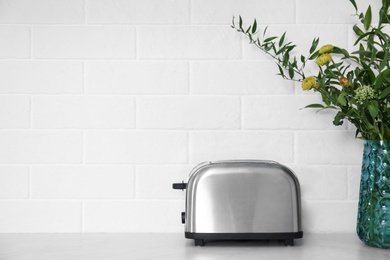 Modern stainless steel toaster on countertop in kitchen. Space for text