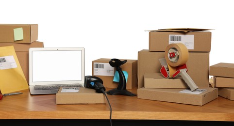 Parcels, laptop and barcode scanner on wooden table against white background. Online store