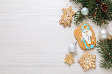 Photo of Tasty gingerbread cookies and festive decor on white wooden table, flat lay with space for text. St. Nicholas Day celebration