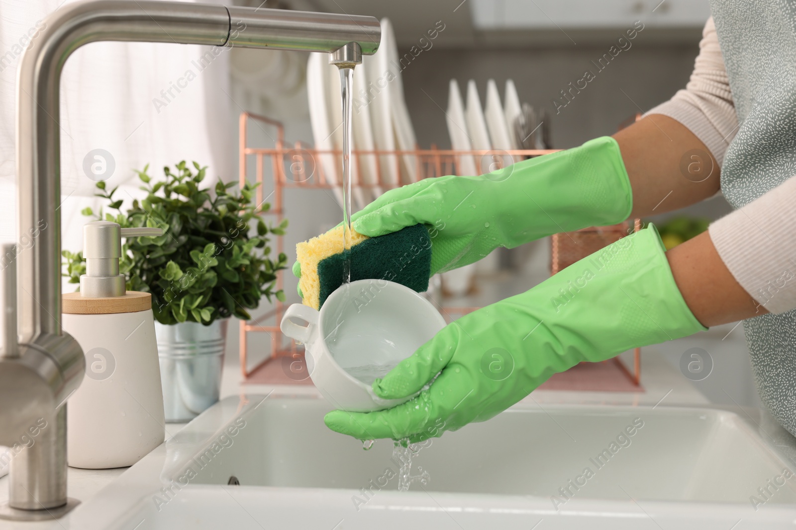 Photo of Woman washing cup at sink in kitchen, closeup