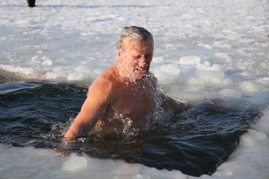 MYKOLAIV, UKRAINE - JANUARY 06, 2021: Mature man immersing in icy water on winter day