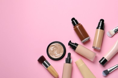 Liquid foundations and beauty accessories on pink background, flat lay. Space for text