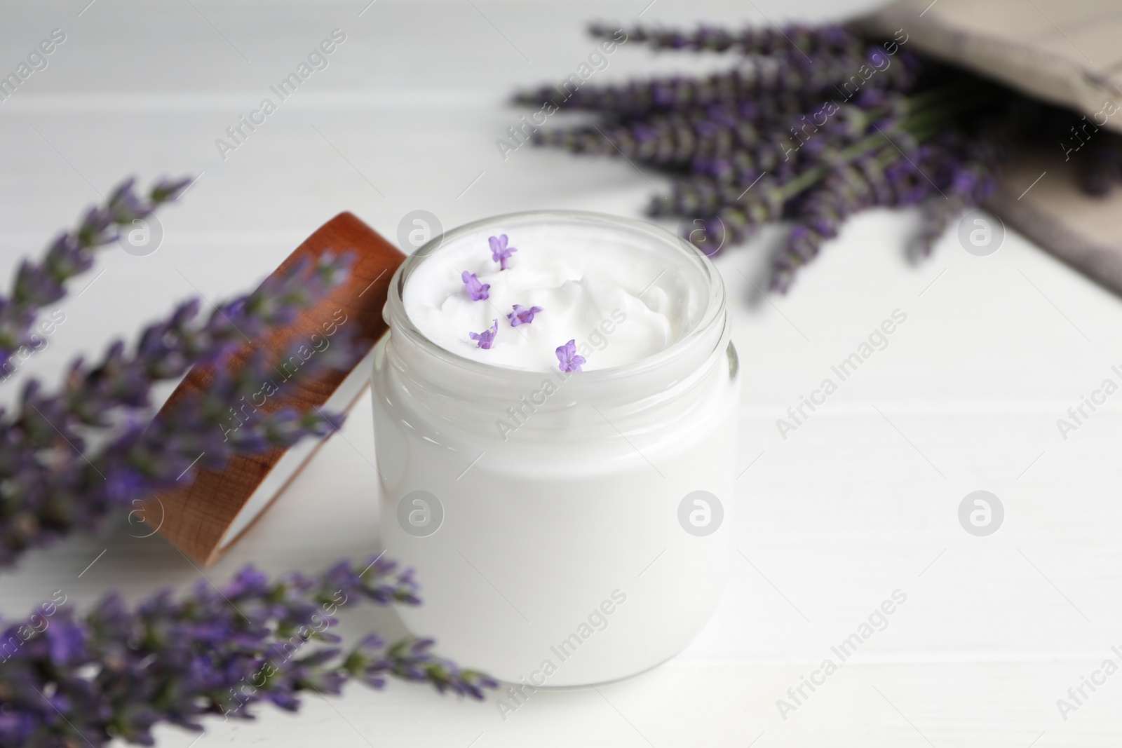 Photo of Jar of face cream and beautiful lavender on white wooden table