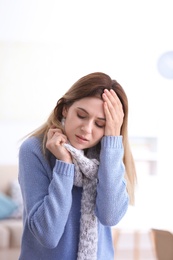 Woman with headache suffering from cold on blurred background