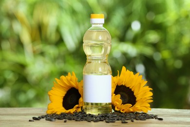 Sunflower cooking oil, seeds and yellow flowers on wooden table outdoors