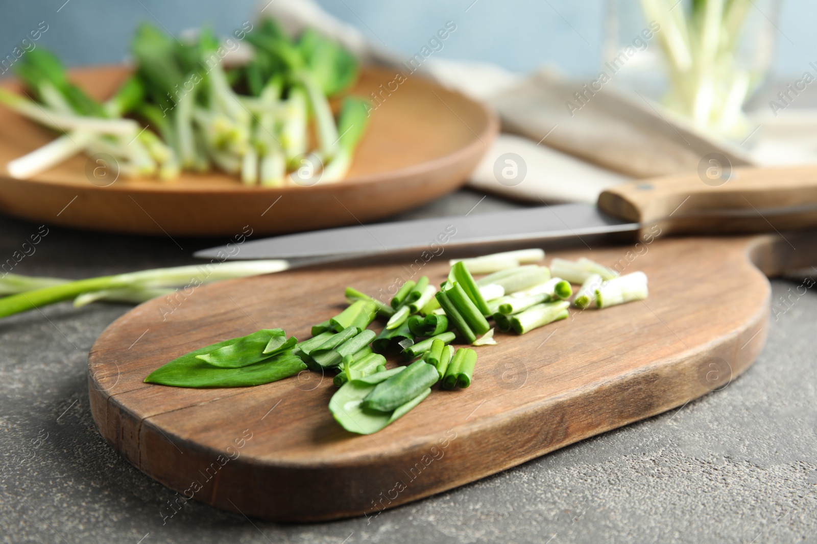 Photo of Board with wild garlic or ramson on grey table, closeup