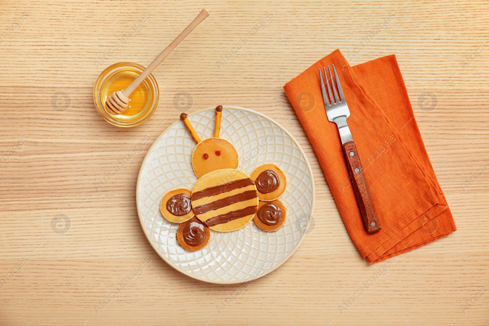 Photo of Flat lay composition with pancakes in form of bee on wooden background. Creative breakfast ideas for kids