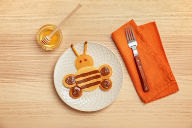 Flat lay composition with pancakes in form of bee on wooden background. Creative breakfast ideas for kids