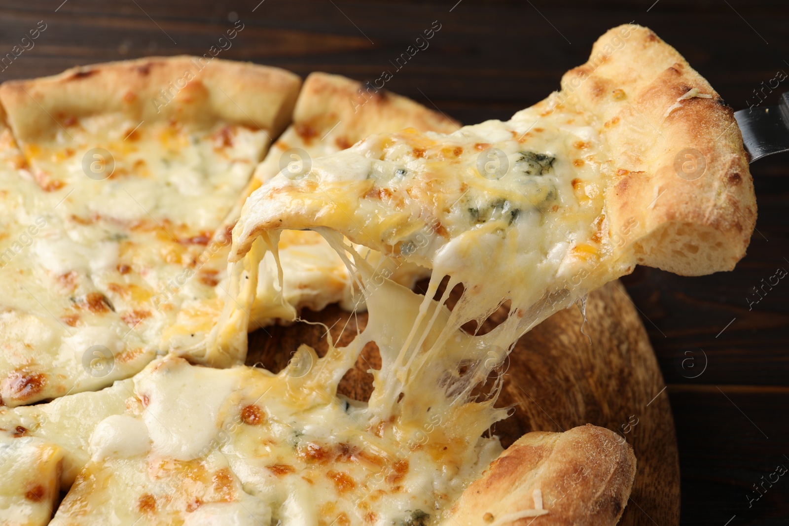 Photo of Taking piece of delicious cheese pizza at wooden table, closeup