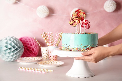 Photo of Woman putting stand with fresh delicious cake on against color background, closeup. Space for text