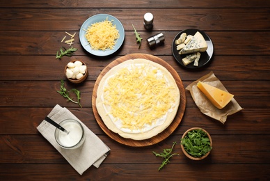 Flat lay composition with pizza crust and ingredients on wooden table