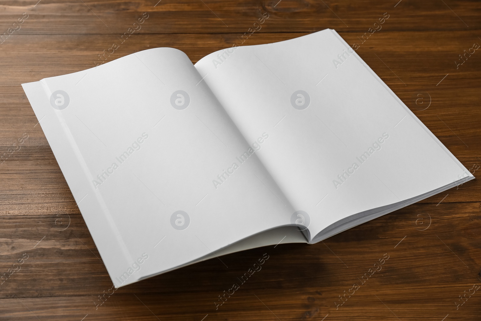 Photo of Open blank paper brochure on wooden table. Mockup for design