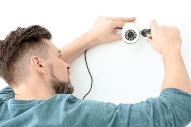 Photo of Technician installing CCTV camera on wall indoors