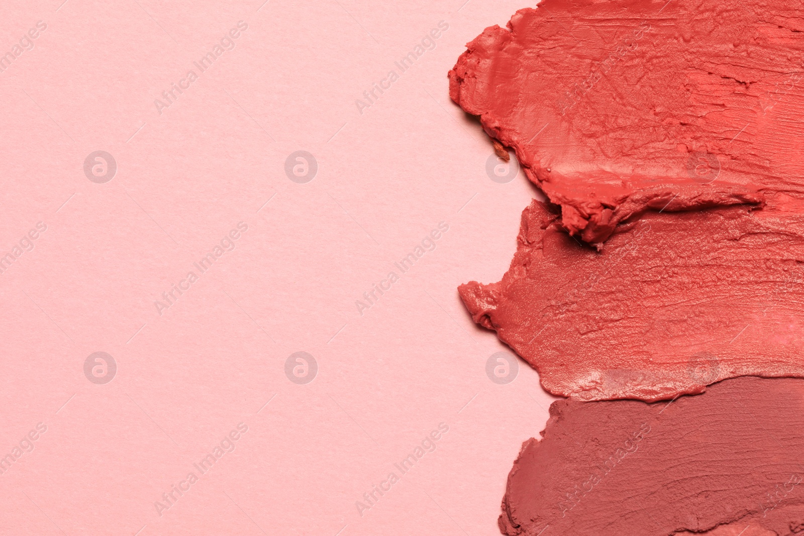 Photo of Smears of beautiful lipsticks on pink background, top view. Space for text