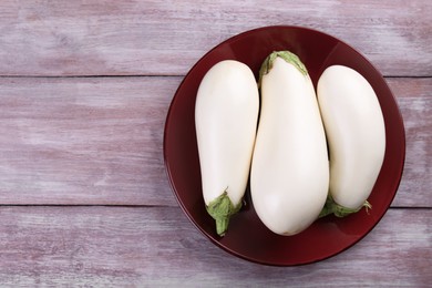 Photo of Fresh white eggplants on wooden table, top view. Space for text