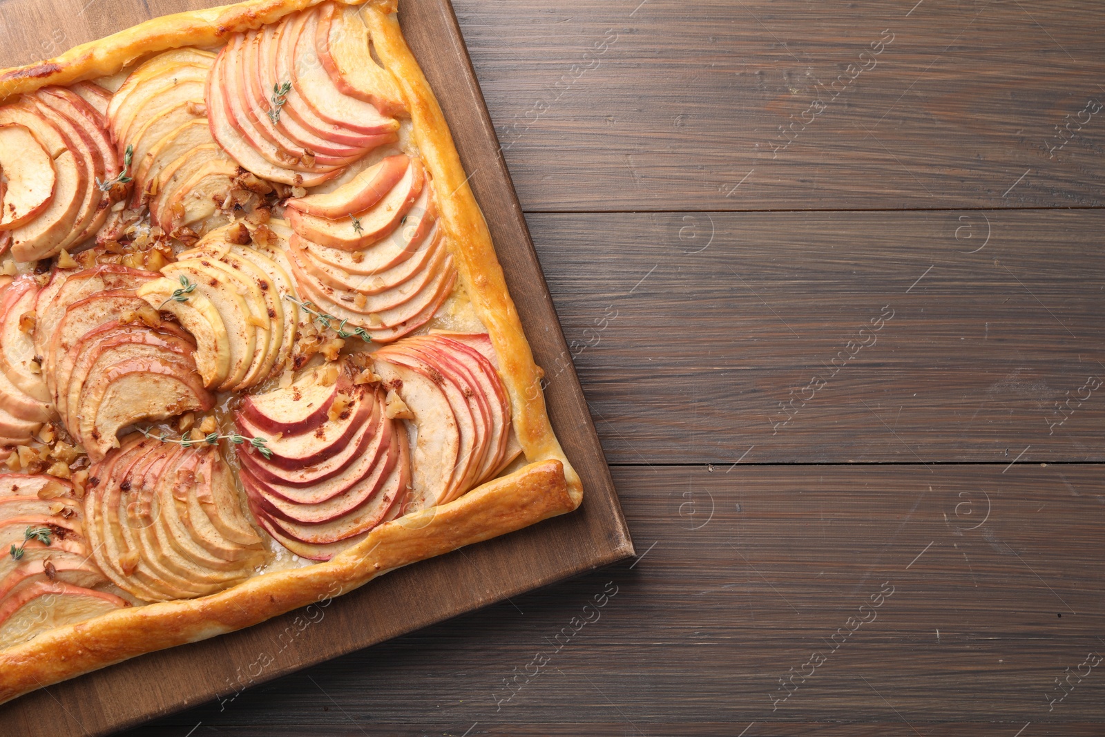 Photo of Freshly baked apple pie with nuts on wooden table, top view. Space for text
