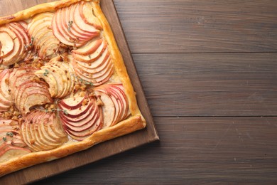 Freshly baked apple pie with nuts on wooden table, top view. Space for text